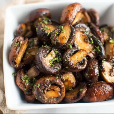 Crispy air fryer mushrooms served in a bowl, garnished with herbs.