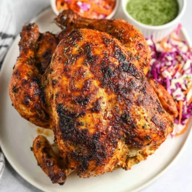 A deliciously golden Air Fryer whole roasted chicken served with herbs and spices.