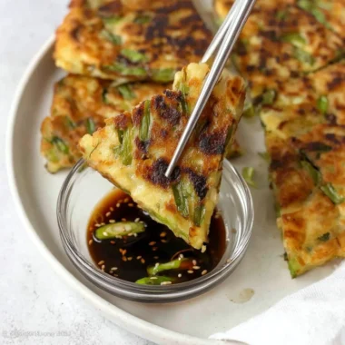Korean scallion pancake served with dipping sauce on a plate