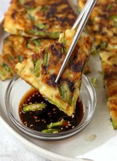 Korean scallion pancake served with dipping sauce on a plate