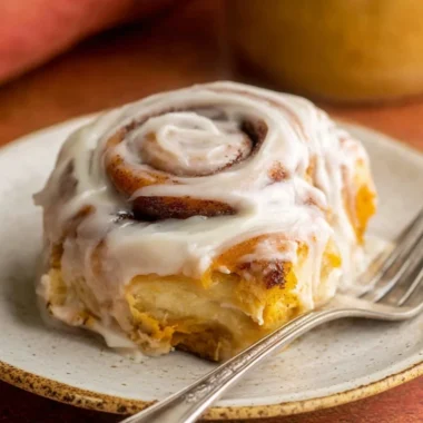 Delicious homemade pumpkin cinnamon rolls topped with creamy icing.