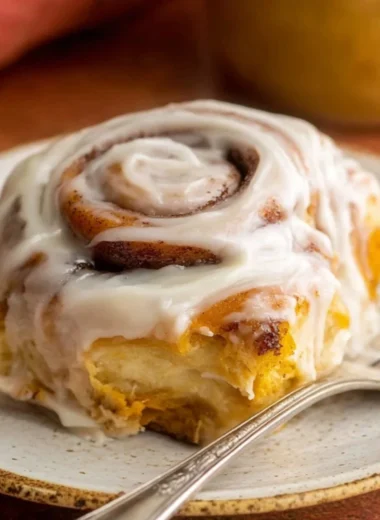 Delicious homemade pumpkin cinnamon rolls topped with creamy icing.