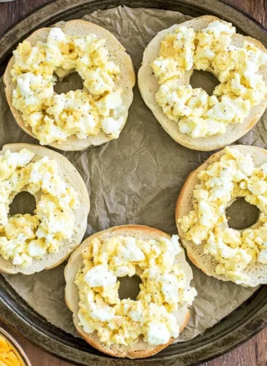 Homemade breakfast pizza bagels topped with eggs, cheese, and vegetables.