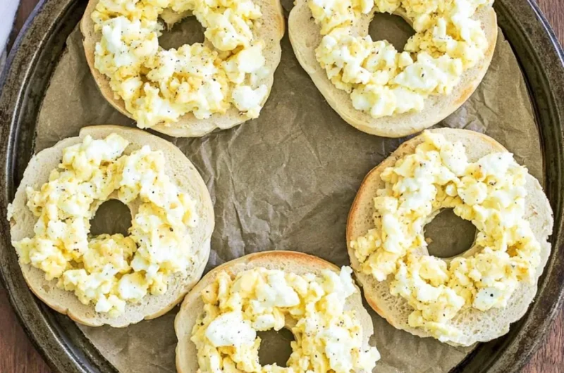 Homemade breakfast pizza bagels topped with eggs, cheese, and vegetables.