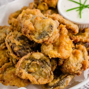 Plate of golden, crispy fried mushrooms ready to be served as a tasty snack