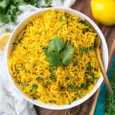Bowl of vibrant turmeric rice garnished with herbs and spices