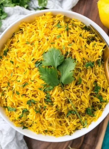 Bowl of vibrant turmeric rice garnished with herbs and spices