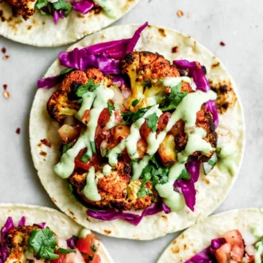 Vegan roasted cauliflower tacos topped with fresh cilantro and lime.