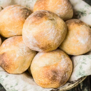 Freshly baked crusty sourdough rolls on a rustic wooden table