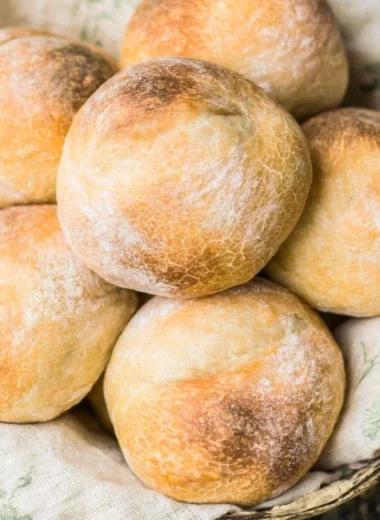 Freshly baked crusty sourdough rolls on a rustic wooden table