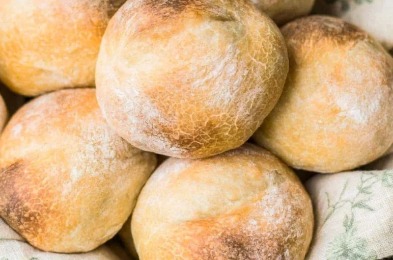 Freshly baked crusty sourdough rolls on a rustic wooden table