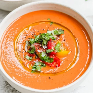 Bowl of easy vegan gazpacho garnished with fresh herbs and vegetables.