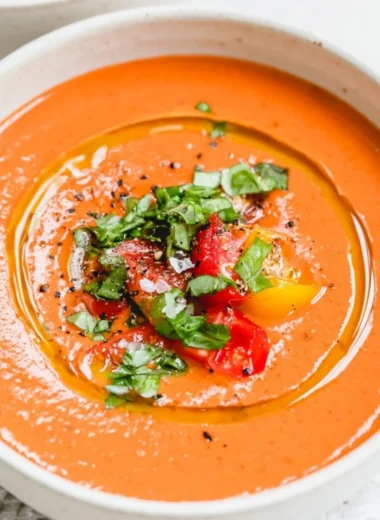 Bowl of easy vegan gazpacho garnished with fresh herbs and vegetables.