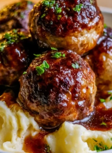 Salisbury steak meatballs served with garlic herb mashed potatoes on a plate.
