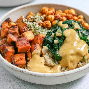 Colorful sweet potato grain bowl topped with fresh vegetables and herbs