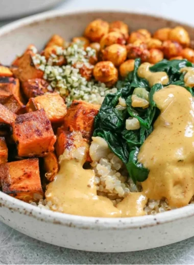 Colorful sweet potato grain bowl topped with fresh vegetables and herbs
