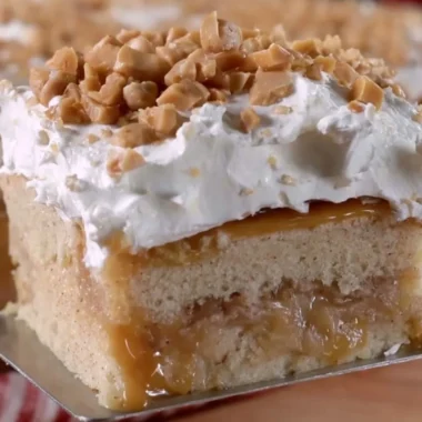 Delicious caramel apple poke cake topped with caramel drizzle and apple slices.