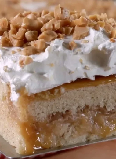 Delicious caramel apple poke cake topped with caramel drizzle and apple slices.