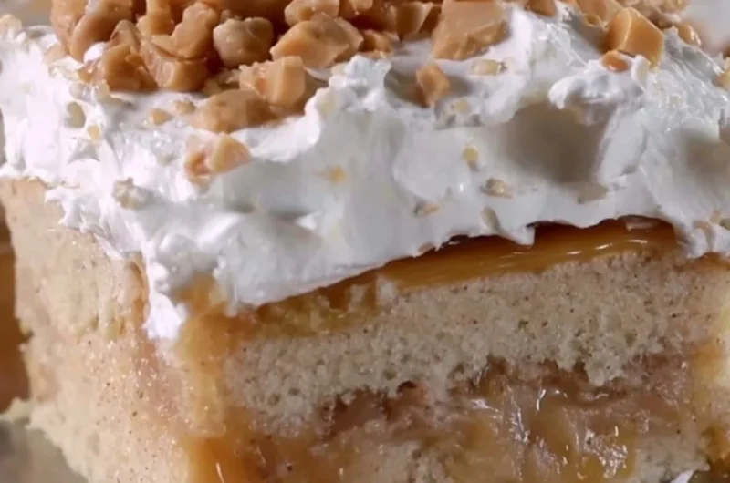 Delicious caramel apple poke cake topped with caramel drizzle and apple slices.